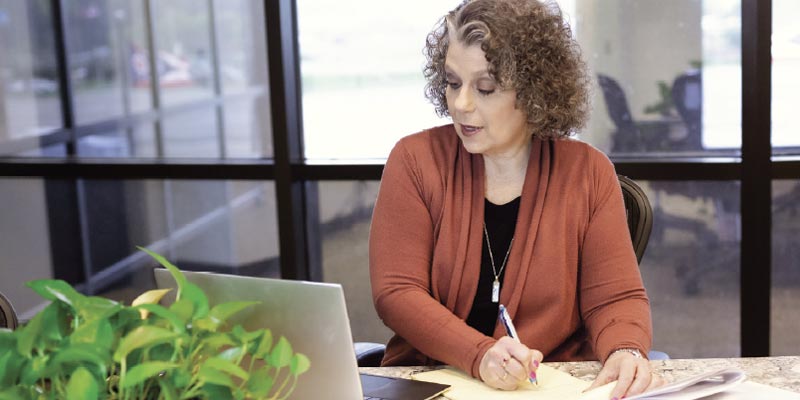 Teresa Zumwald writing notes while looking at her laptop.