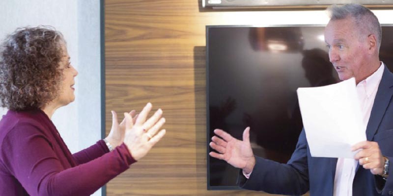 Teresa Zumwald, with arms outstretched, enthusiastically speaking with another business professional.