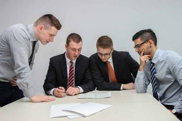 Four men looking at a document on a table.