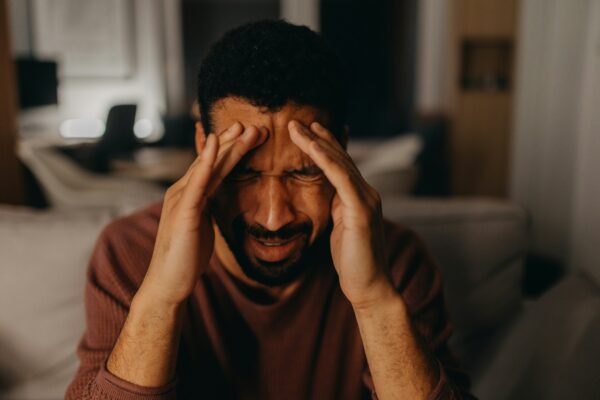 Man grimacing with his hands on the sides of his head and forehead
