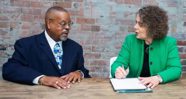 Teresa Zumwald speaking with a male client, while taking notes.
