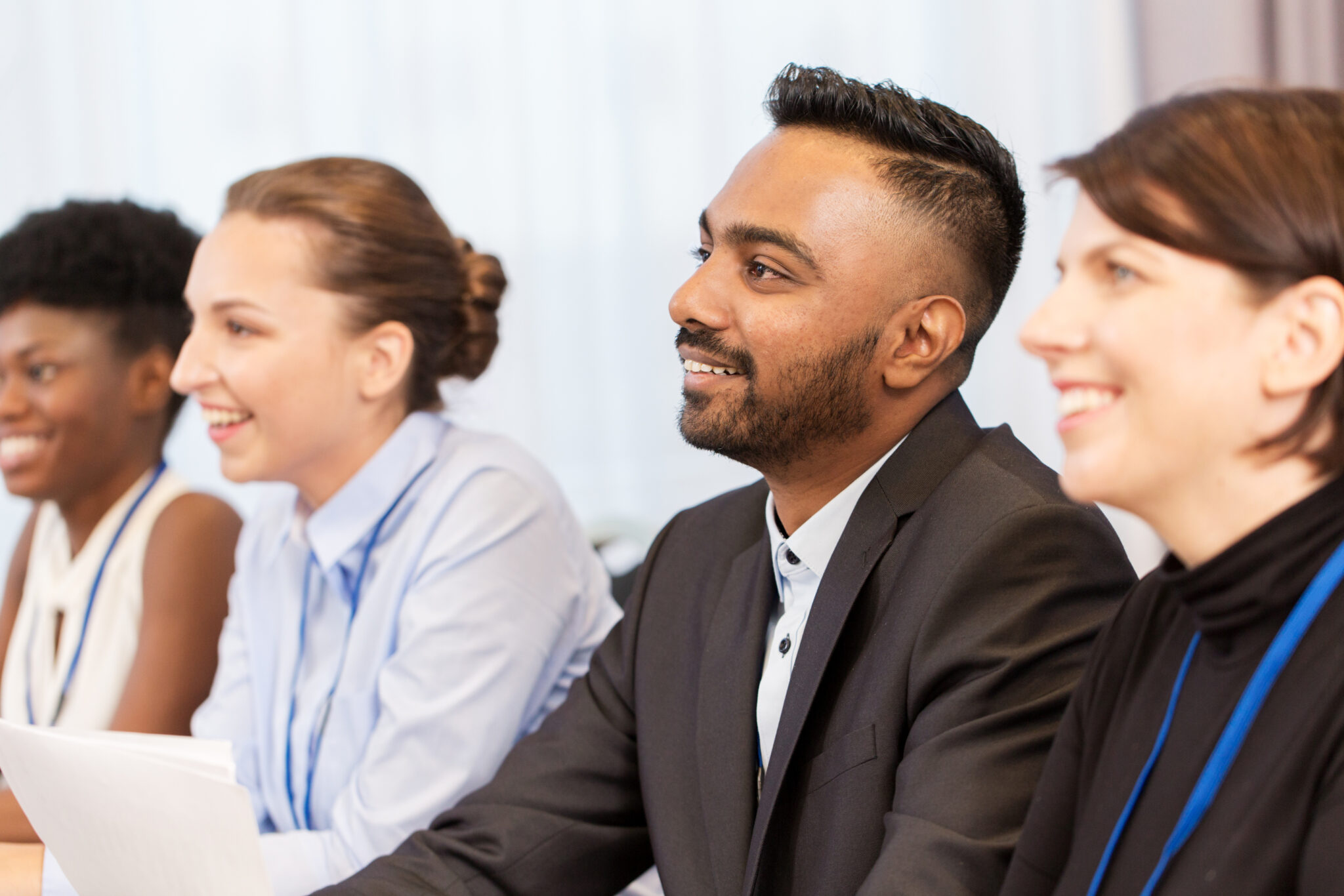 Group of people listening to someon off view, with a text overlay with link to "Our Clients"