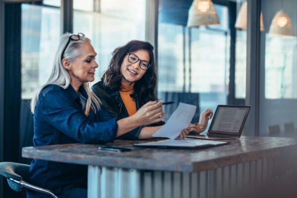 Two women analyzing documents at office. 