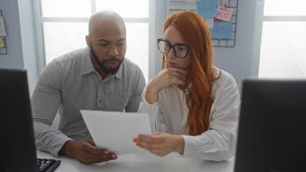 Man and woman collaborating in an office, examining documents amid modern indoor setting