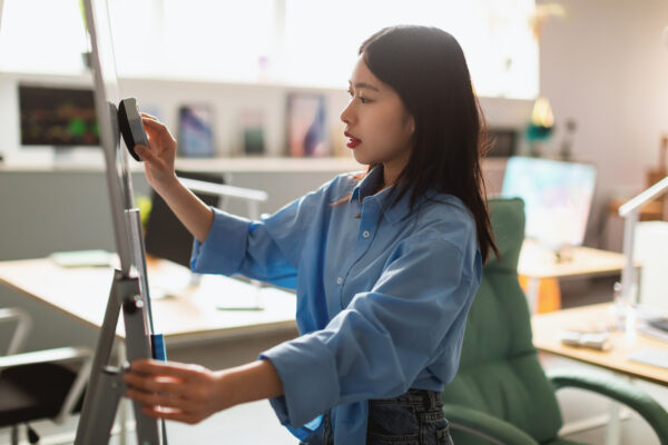 Asian Businesswoman Wiping Whiteboard, Preparing Presentation